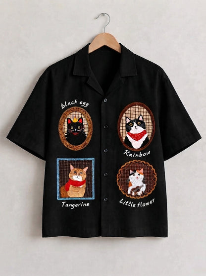 A black short-sleeve button-up shirt hanging on a wooden hanger against a light gray wall. The shirt features four embroidered cat designs on the front, labeled 'black egg', 'Rainbow', 'Tangerine', and 'Little flower'.