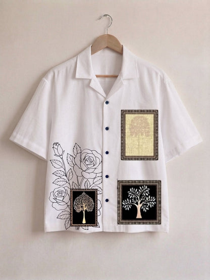 A white short-sleeve button-up shirt hanging on a wooden hanger against a light beige wall. The shirt features black line-art rose graphics on the lower left chest, and two square decorative panels on the right chest with tree-of-life designs in black, white, and gold.